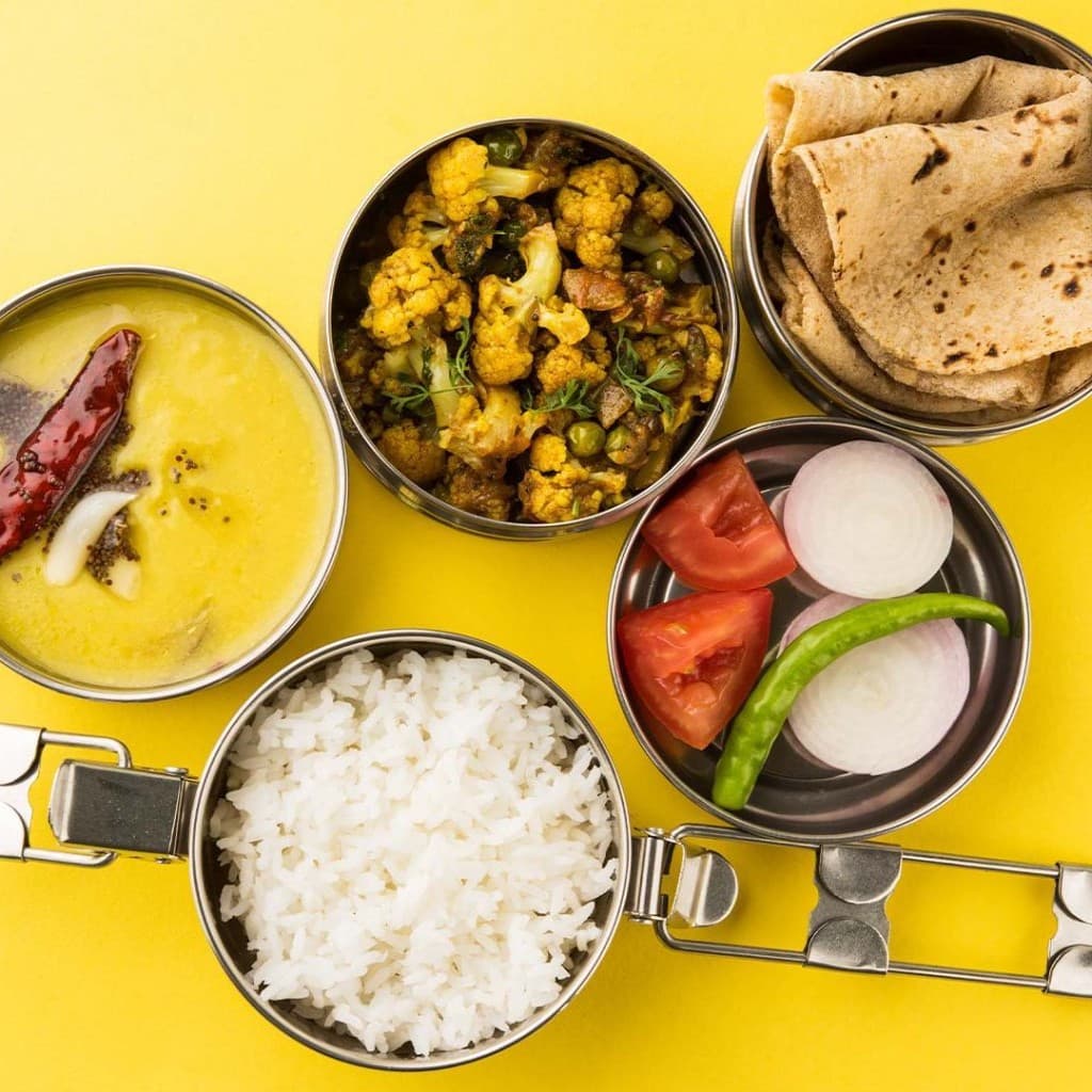 Home-style vegetarian tiffin — dal, rice, sabzi, roti, and salad in steel containers from HomeRasoi